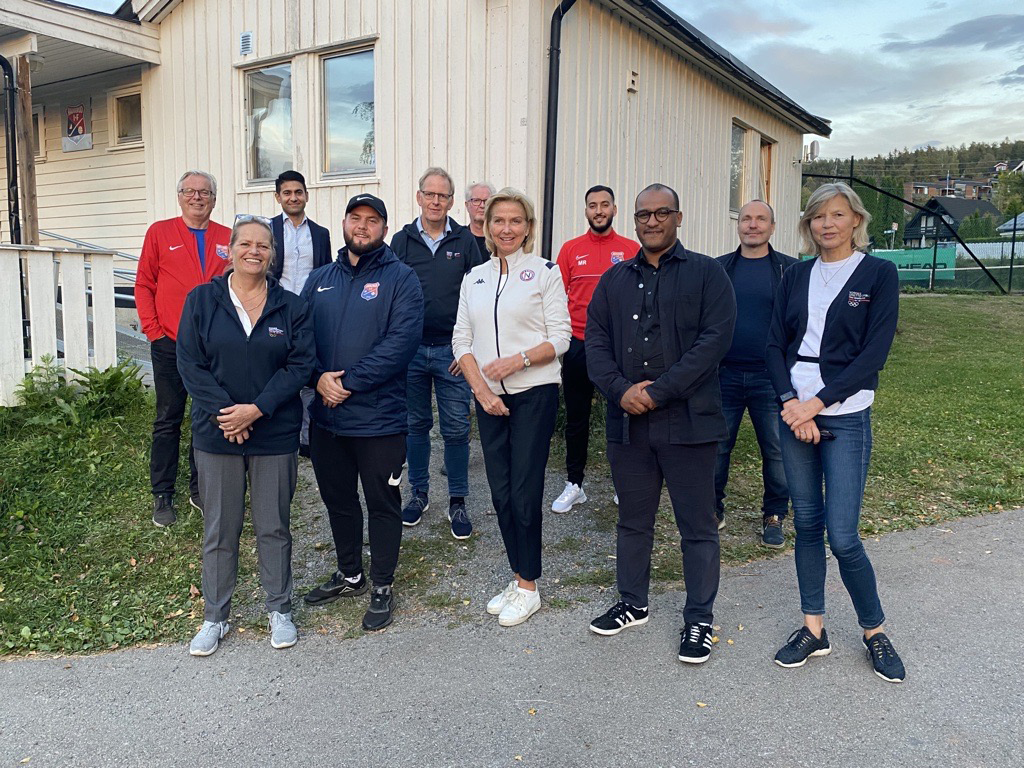 Representanter fra Haugerud IF, Oslo kommune, Oslo idrettskrets og bydel Alna samlet med idrettspresident Berit Kjøll foran det dugnadsbygde klubbhuset i Groruddalen. Foto: Per Tøien