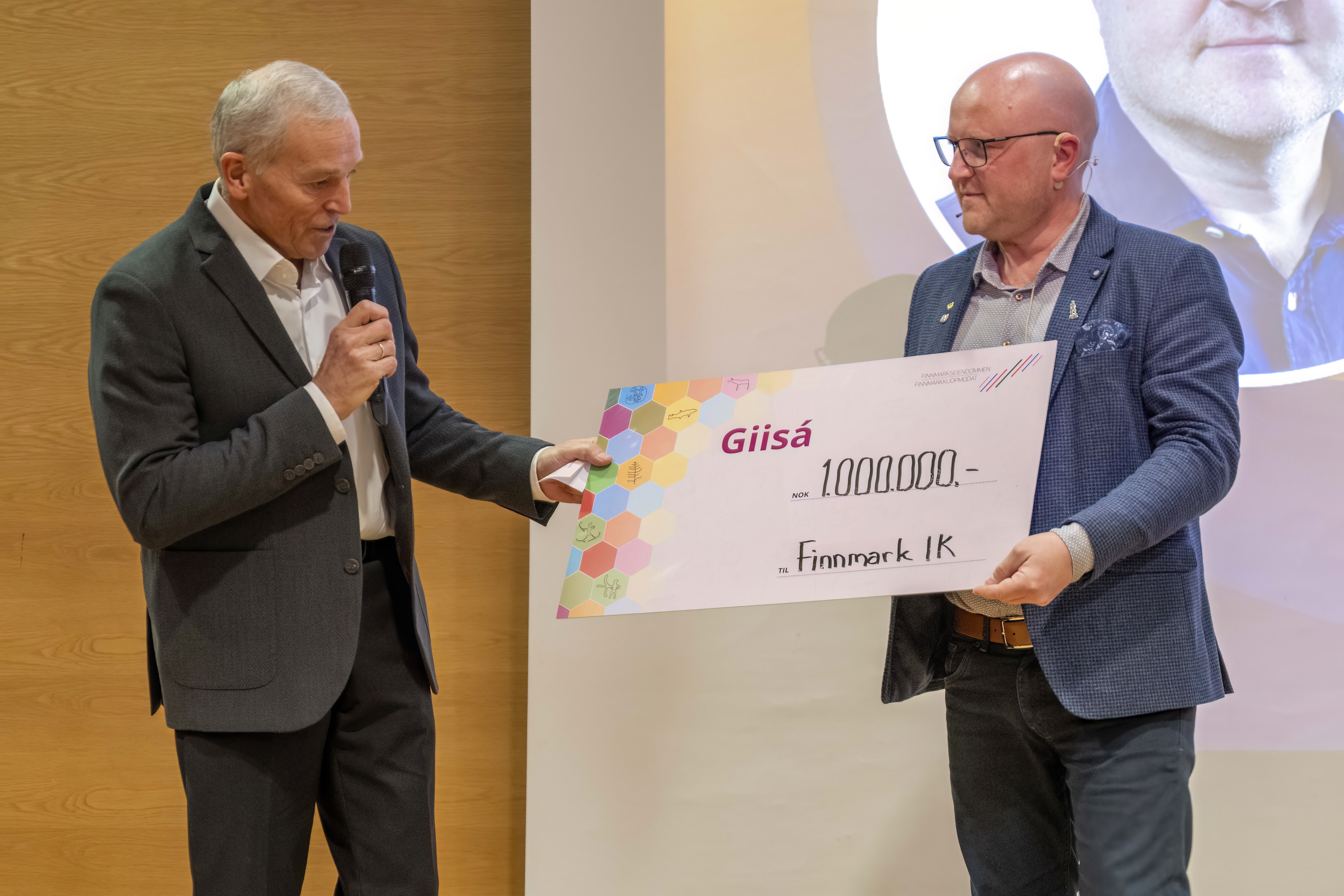 Styreleder i Finnmarkseiendommen, Thomas Arild Mølmann, overrekker sjekken med 1 million kroner til Finnmark idrettskrets' styreleder, Geir Knutsen.