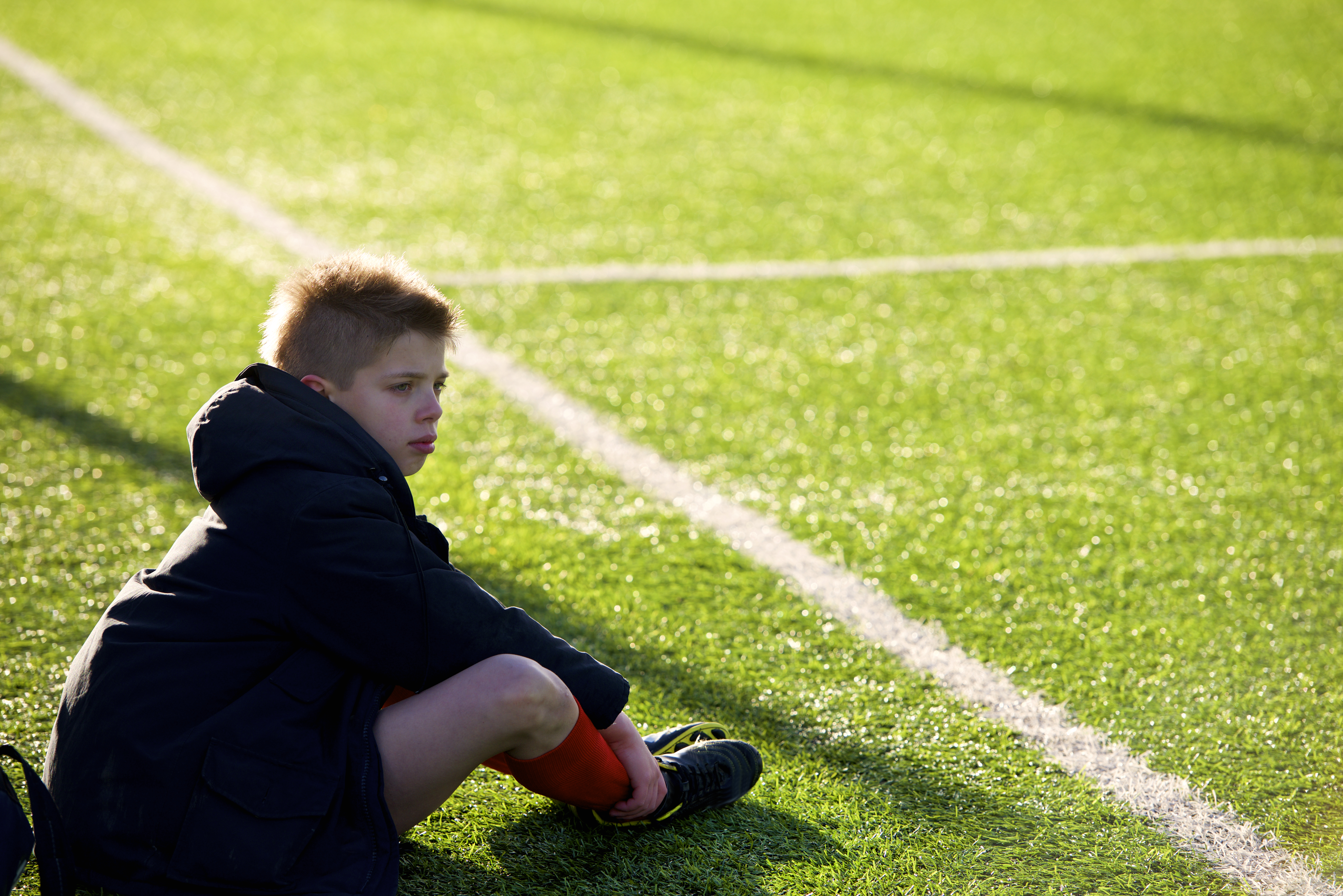 Illustrasjonsbilde: en gutt som sitter på fotballbanen og er litt lei seg